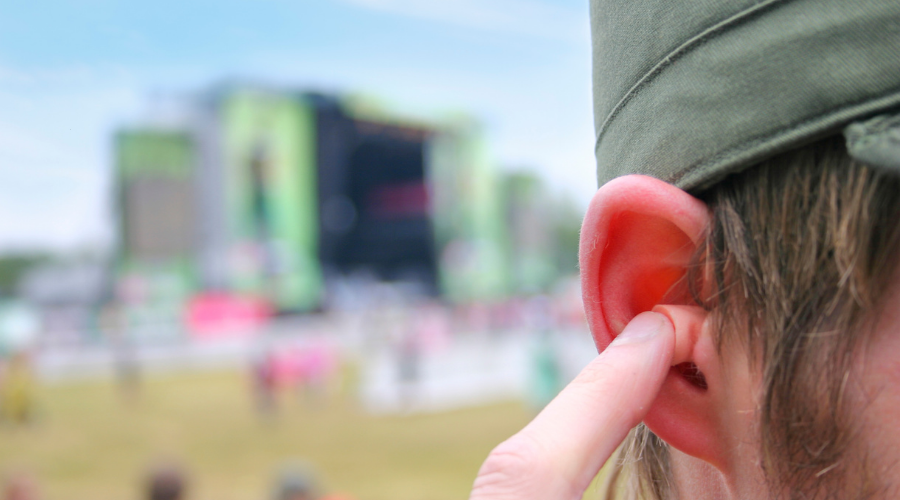 Festivalganger gebruikt oordoppen om gehoor te beschermen tegen harde muziek.