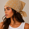Bruine bandana gedragen door model – klassieke paisley bandana in bruin met witte print, gedragen als hoofddoek. Veelzijdig te stylen als haarband, nekdoek of accessoire. Ideaal als cadeau of festival- en zomeraccessoire.